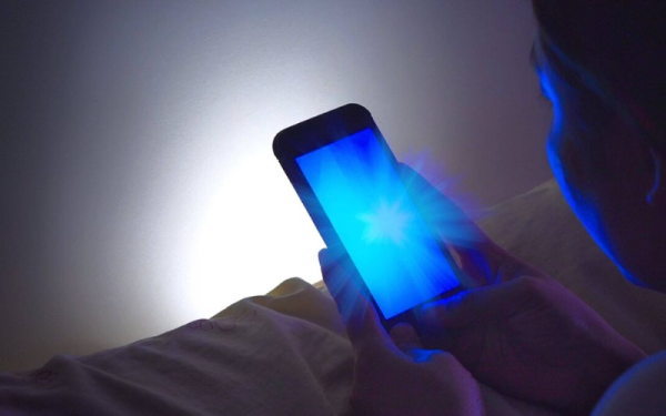 Móvil con luz azul en habitación oscura